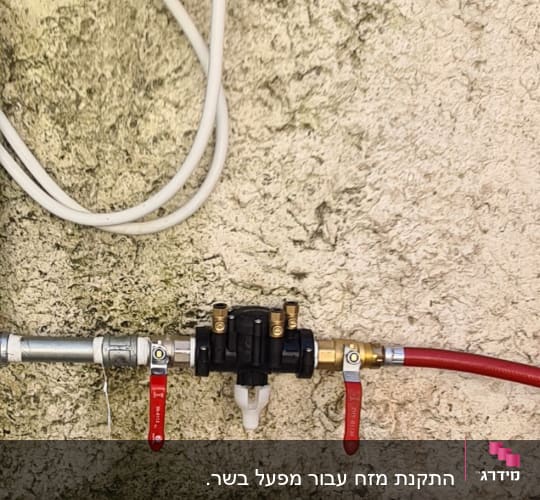 צינורות מים עם ברזים אדומים על קיר